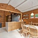 Küche und Essbereich mit Holzwand, weißem Boden und Holzmöbeln.