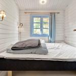 Schlafzimmer mit Bett, Fenster und Wandlampen in weißer Holzwand.