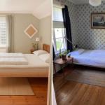 Zwei Schlafzimmer mit Betten, Fenstern und Holzböden. Ein Raum hat gemusterte Tapete.