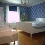 Zwei Betten mit weißen Laken, blaue Tapete und Holzboden im Schlafzimmer.