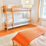 Zimmer mit Doppelstockbett und Einzelbett, Holzboden und Fenster mit Blick.