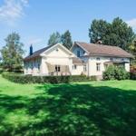 Haus mit großem Garten und Terrasse unter Bäumen.
