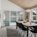 Essbereich mit Tisch, Stühlen und Blick auf Pool und Garten.