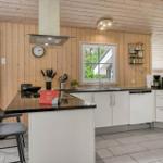 Moderne Küche mit Holzwand, weißer Arbeitsplatte und Kücheninsel mit Barhockern.