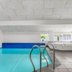 Indoorpool mit Dusche und Whirlpool. Fenster bieten Tageslicht.