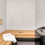 Sauna mit Holzbank und Steinkasten. Weiße Wände und gefaltete Handtuch.