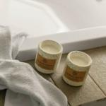 Zwei Kerzen und ein Handtuch neben einer Badewanne.