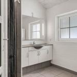 Badezimmer mit Waschbecken, Spiegel und Fenster. Dusche mit Glaswand.
