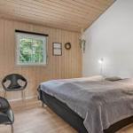 Schlafzimmer mit Bett, Fenster und zwei Stühlen. Holzwand und Decke.