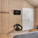 Schlafzimmer mit Holzwand, Bett, Kleiderschrank, TV und zwei Stühlen.