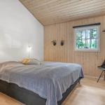 Schlafzimmer mit Bett, Fenster und Stuhl. Holzwände und Decke.