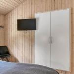 Schlafzimmer mit Holzwand, Bett, KleiderSchrank, TV und Stuhl.