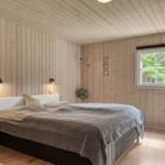 Schlafzimmer mit Holzwandverkleidung, Bett, Fenster und Nachttisch.