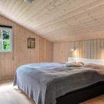 Schlafzimmer mit Holzwand, Bett, Fenster und Stuhl