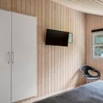 Schlafzimmer mit Bett, Kleiderschrank, TV und Fenster zum Garten.