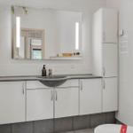Badezimmer mit Spiegelschrank, Waschbecken und Toilette.