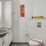 Badezimmer mit Waschbecken, Toilette und Wandbildern.