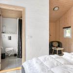 Schlafzimmer mit Bett, Fernseher und Sitzgelegenheit. Nebenraum mit Toilette und Dusche.