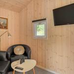 Raum mit Holzwand, Fernseher, Sessel und Tisch mit Fernbedienung.