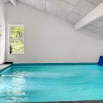 Innere Schwimmhalle mit blauem Wasser und Fenster zur Natur.