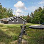 Ein graues Haus mit Spielplatz und Trampolin im Garten.