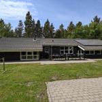 Ein modernes Haus mit Terrasse, Garten und Blick auf einen Wald.