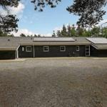 Schwarzes Haus mit Solaranlage und Garten. Außenbereich mit Tisch und Stühlen.