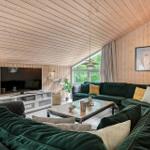 Wohnzimmer mit grünem Sofa, Fernseher und Holzwand.