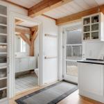 Küche mit weißen Schränken, Glasfronten und Blick in das Badezimmer.