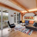 Wohnzimmer mit Ledersofa, Glasfront und Holzbalkendecke.