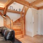 Wohnbereich mit Holztreppe, Sofa und Deckenbalken.