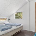 Schlafzimmer mit Doppelbett, Holzwand und Fensterblick auf Wald.