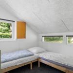 Zwei Einzelbetten, Fenster mit Waldblick, Holzschränke und schlichte Wandgestaltung.