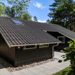 Holzhütte mit dunkler Fassade und Dachgauben im Wald.