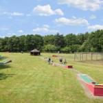 Großer Grünbereich mit Minigolfanlage und Holzschuppen im Hintergrund.