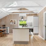 Küche mit Essbereich und Schlafzimmer. Holzwände und Dachfenster.