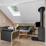Wohnzimmer mit Sofa, Sessel und Kaminofen unter Dachschrägen.