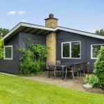 Ein modernes Haus mit Terrasse, Garten und Grillplatz. Fenster und Holzverkleidung sind sichtbar.