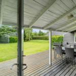 Terrasse mit Tisch und Stühlen, Blick auf grünen Garten und Hecke.
