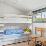 Zimmer mit Doppelstockbett, Fenster und Holzstühlen.