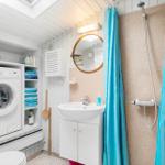 Badezimmer mit Waschmaschine, Dusche und Waschbecken.