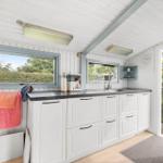 Küche mit weißen Schränken, Arbeitsfläche und Fenster zum Garten