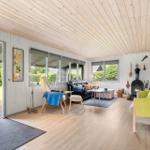 Wohnzimmer mit Holzdecke, Kamin und Blick auf den Garten.