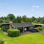 Ein Haus mit Terrasse, Garten und Grillplatz. Umgeben von Bäumen und Gras.