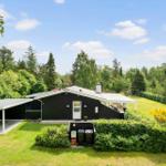 Schwarzes Haus mit Garage und Terrasse im grünen Garten