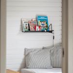 Ein Bett mit Streifenkissen und einem Bücherregal an der Wand.