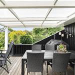 Terrasse mit Tisch, Stühlen und Liegestühlen unter einem weißen Dach.
