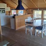 Kitchen and dining area with wooden ceiling and windows. Dining table with chairs and kitchen counter.