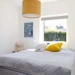 Bedroom with bed, window, mirror, and stuffed bear.