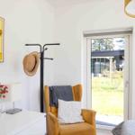 A room with a yellow chair, wall art, and view of the garden.
